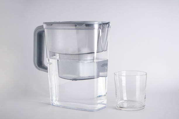 istock Water filter jug and a glass of water on a grey background. Close-up. 1433856467