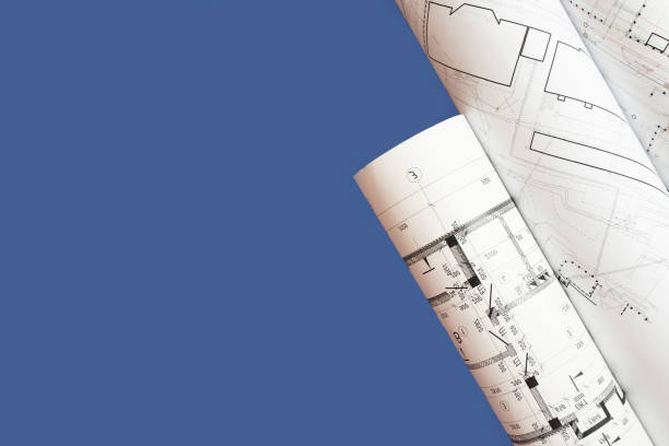 istock Paper architectural drawings and blueprint rolls on a blue background, copy space 1433859736