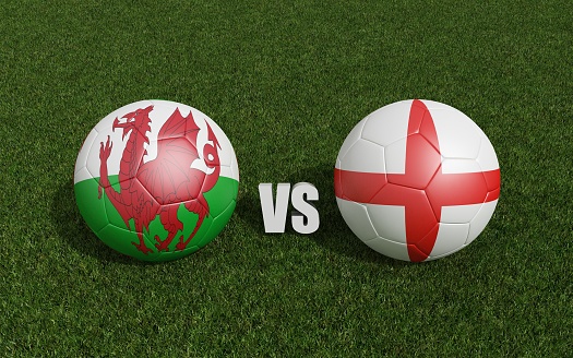 Footballs in flags colors on grass . Wales with England. Football championship. 3d rendering