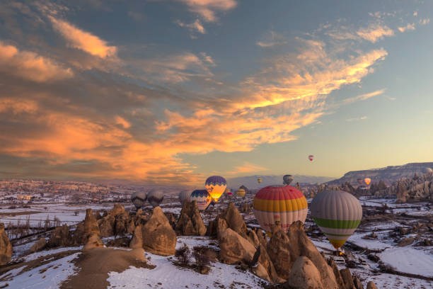 Editorial Goreme hot air balloons Hot Air balloons fly over Mountains landscape in winter during sunrise in Cappadocia, Goreme National Park, Turki. Goreme, Turkey - February 12 2022. cappadocia winter photos stock pictures, royalty-free photos & images