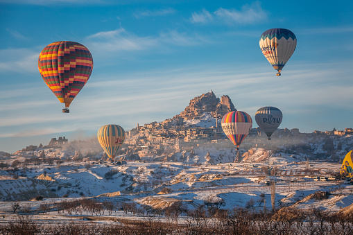 Hot Air balloons fly over Mountains landscape in winter during sunrise in Cappadocia, Goreme National Park, Turki. Goreme, Turkey - February 12 2022.