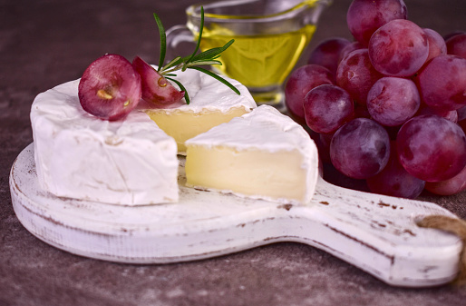 Camembert cheese and grapes on a white wooden board.Close-up.
