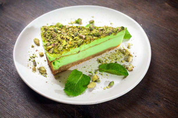 Pistachio cheesecake portion with matcha flavor and mint. A bright green piece of dessert on a plate. stock photo