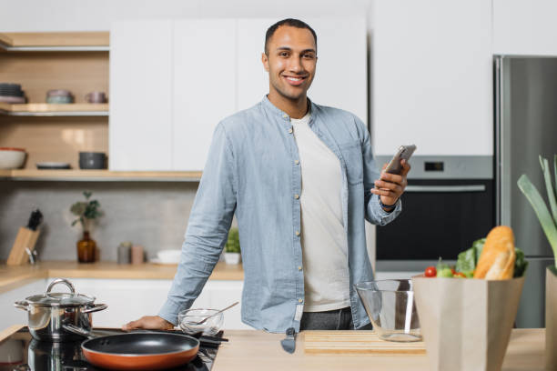 istock Happy young indian man using smartphone standing in kitchen in the morning. 1433883224