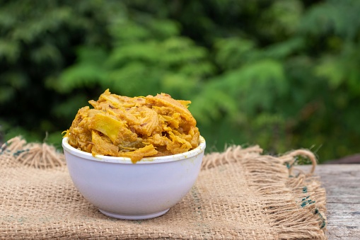 Closeup of Chalta Chutney or Dillenia Indica Curry in a Bowl on Burlap Fabric with Copy Space in Horizontal Orientation, Also Known as Elephant Apple Curry.