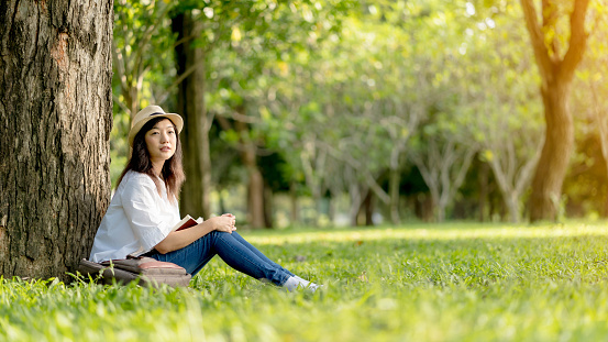 Beautiful woman wearing white shirt and white hat Enjoying a Book Reading and relaxation