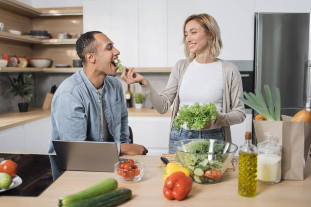 istock Blond young wife spouses having fun while feeding her husband with lettuce salad 1433894093