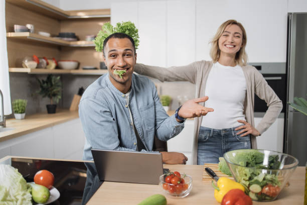 istock Multiethnic couple using laptop computer while preparing together healthy food diet vegetable salad 1433894109
