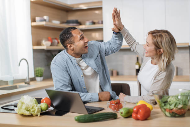 istock Attractive couple using laptop computer while preparing together healthy food giving high five 1433894421