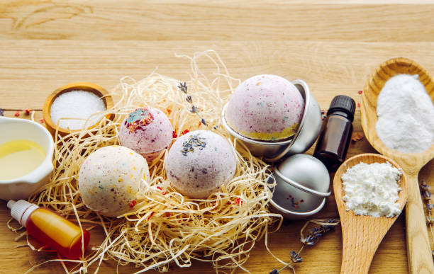 Making fizzy bath bombs at home concept. All the ingredients on table on wood spoons: cornstarch, essential oil, dye, citric acid, baking soda, dry herbs, round metal pressing molds. Copy space. concepto de fabricación de bombas de baño gaseosas en casa. todos los ingredientes en la mesa en cucharas de madera: almidón de maíz, aceite esencial, tinte, ácido cítrico, bicarbonato de sodio, hierbas secas, moldes redondos de prensado de metal. es