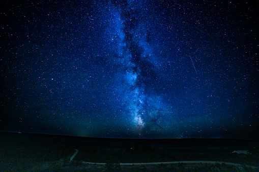 Milky Way and shooting stars in night sky over wildlife dirt road and the Missouri River in the Charles M Lewis Wildlife Refuge in northern Montana, western USA.