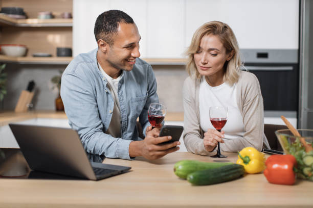 istock Smiling young spouses having delicious healthy breakfast together and using cell phone 1433896012