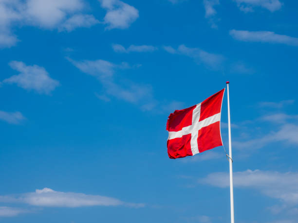 istock Danish flag dannebrog against blue sky with clouds 1433896045