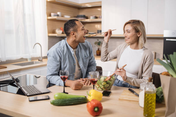 istock Cheerful married multinational couple using laptop while cooking healthy food in kitchen 1433896226