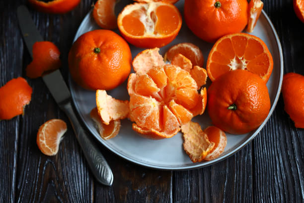 Juicy ripe tangerines on a plate. Peeling a tangerine. Skins of citrus. stock photo