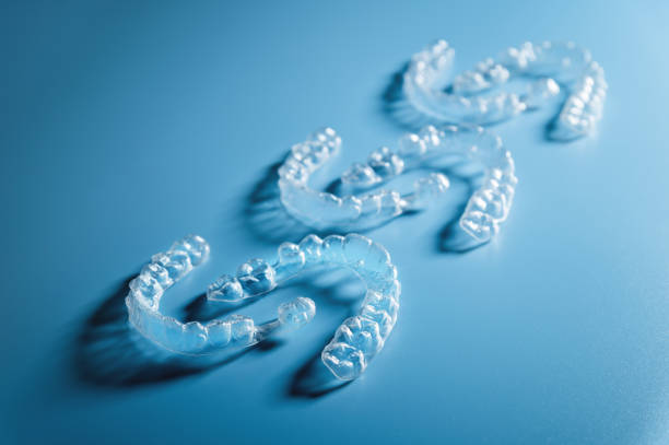 Close up invisible aligners on blue background with copy space. Plastic braces for teeth alignment. Set of three pairs of aligners on a blue background stock photo