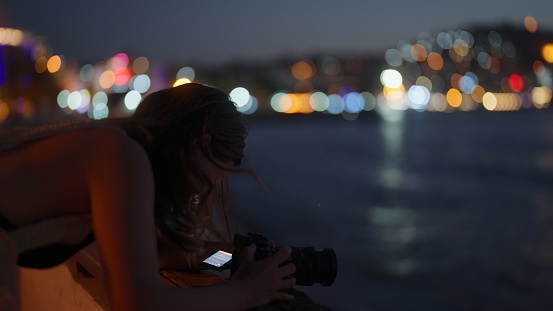 A young female tourist is taking photos and videos of seascape during her travel.