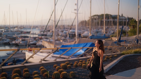 A young female tourist is taking a walk at harbor during sunset.