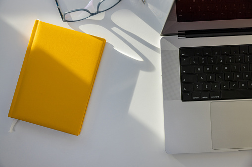 High angle view of laptop, eyeglasses and yellow personal organizer on the desk