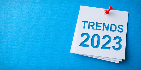 Trends 2023 Word in White Sticky Note on Blue Cardboard Background