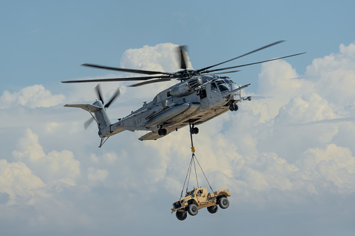 Helicopter carrying  a all terrain vehicle that is attached by a rope.  Photo taken in non ticket area Miramar Airbase in San Diego California USA on September 23, 2022.