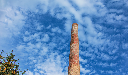 The pipe of a gas boiler house against the blue sky. No smoke comes out of the chimney. Energy crisis.