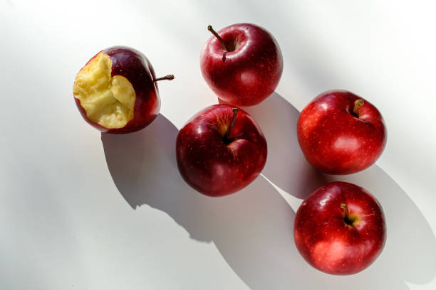 istock Five red ripe apples lying on a white table and their shadows 1433931454