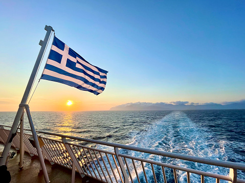 Bandera griega y vista del atardecer desde el ferry entre las islas griegas photo
