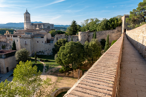 The medieval city wall surrounding the oldest part of the Catalonian city of Girona. The elevated stone walkway runs around the edge of the city, with views down to some of the oldest areas of this popular tourist destination.