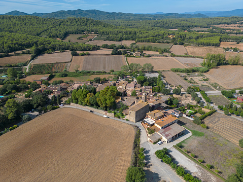 Aerial drone view of the small village of Pubol in the Gerona Province of Catalonia. Once home to the artist Salvador Dali and his wife Gala, who lived in Castle of Pubol, which is now a museum. Ploughed fields surround the village.