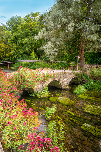 Bibury, flowers stone bridge with flowers near Arlington Row in the England Cotswolds one of the most beautiful villages in the England countryside, UK