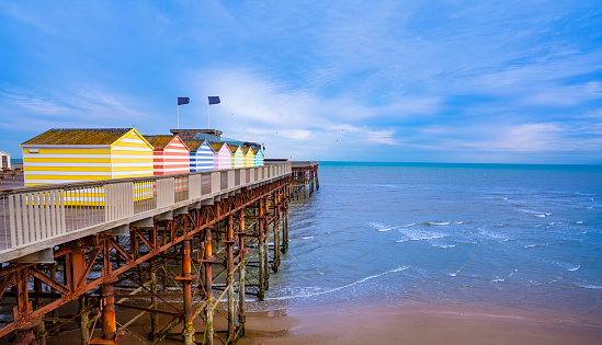 Hastings beach and pier with colorful striped huts resort town in East Sussex England UK United Kingdom
