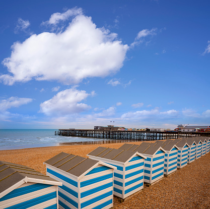 Hastings beach and pier with blue striped huts resort town in East Sussex England UK United Kingdom