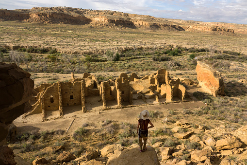 In the morning, a woman hiking enjoys an overlook view of Kin Kletso, a Chocoan great house of Ancestral Pueblo dwellings in New Mexico’s Chaco Culture National Historical Park.