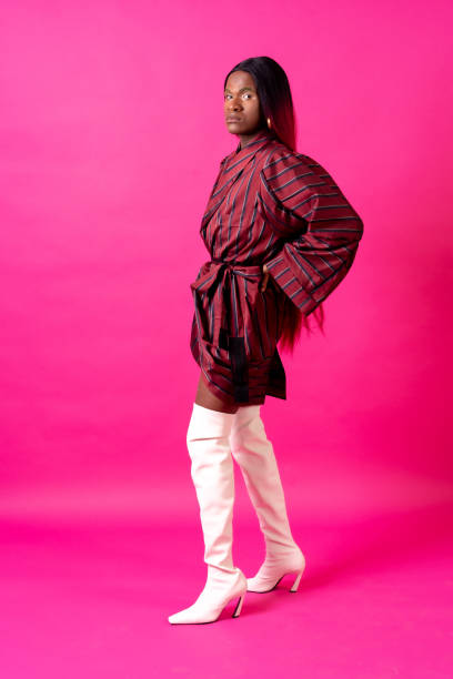 istock Black ethnic man in a studio, LGTBI concept, with a wig on a pink background 1433955121