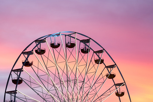 Ferris wheel at the picturesque pink colored sunset