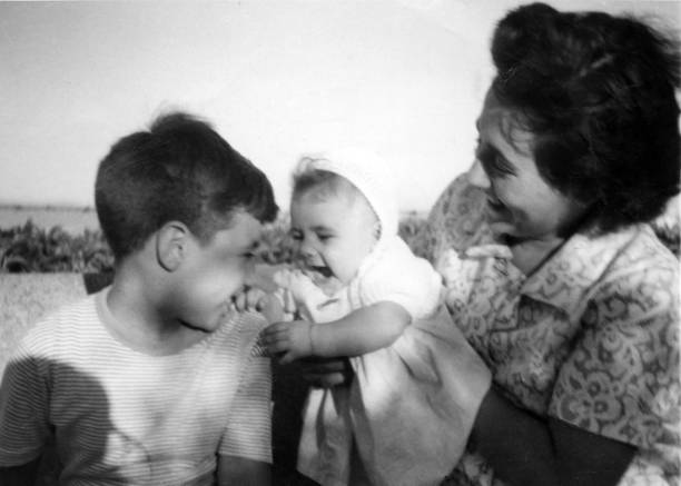 Image taken in the fifties, smiling woman posing with her son and daughter stock photo