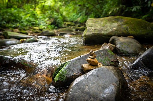 Little yellow rocks stacked on the river, hidden in the forest, next to the hiking trail, background out of focus in purpose, in New Taipei City, Taiwan.