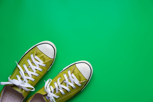 Flat lay of green leather sneaker shoe on green background