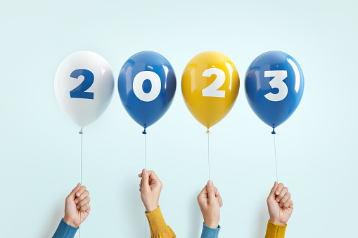 New year number 2023 of balloons in hands on blue background.