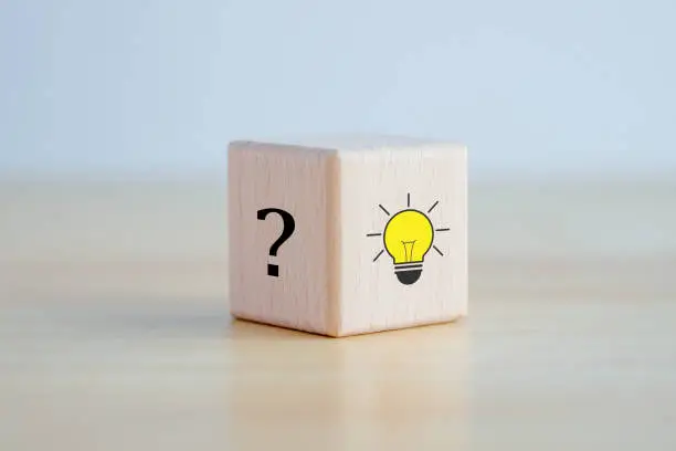 Photo of Idea and creativity concept. Creative process concept and problem solution. Glowing light bulb idea and question mark on wooden block.