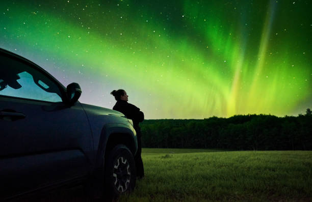 istock Woman standing by her car under Aurora Borealis 1434023580