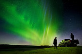 Couple standing by their pick-up truck watching aurora borealis