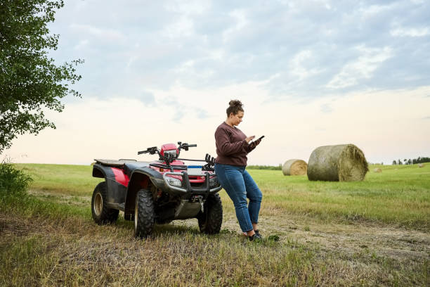 istock Female farmer using mobile phone leaning to ATV on the farm field 1434023659