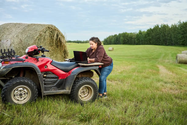 istock Woman using a laptop on quad bike while working on a farm 1434023663
