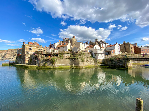 View on a small town of Thouars, France. Many houses with towers and gray roofs among green trees and rooftops. Warm spring morning, vibrant blue sky with clouds, calm atmosphere, skyline