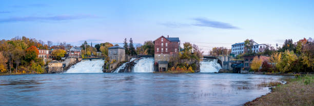 Panorama of the three falls of Vergennes in Vermont in the fall at sunset. The sky is slightly cloudy and pink.