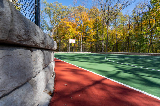 interessanter grüner und roter basketballplatz im freien auf dem schulhof.  der platz umfasst stützmauern und einen schwarzen vinylbeschichteten maschendrahtzaun. - green fence chainlink fence wall stock-fotos und bilder