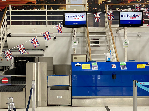 Airport scene at Humberside International airport in Yorkshire in the UK. A closed departure checkin desk in the departures hall. Also with UK national coloured bunting flags hanging up. Possibly a statement about Brexit travel and close borders.