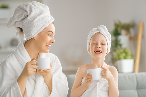Happy family. Mother and daughter child girl are drinking tea after a bath.